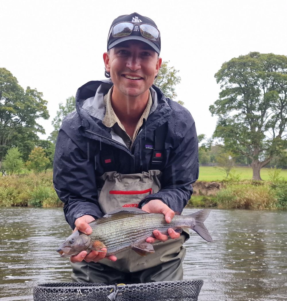Scott Hamilton with a grayling in the rain, river background