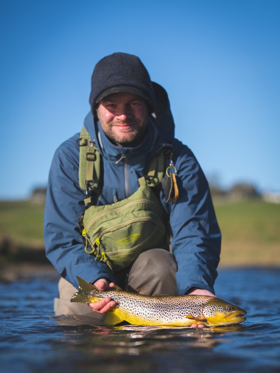 Scott Hamilton with a prize wild brown trout on a Scottish river, blue sky